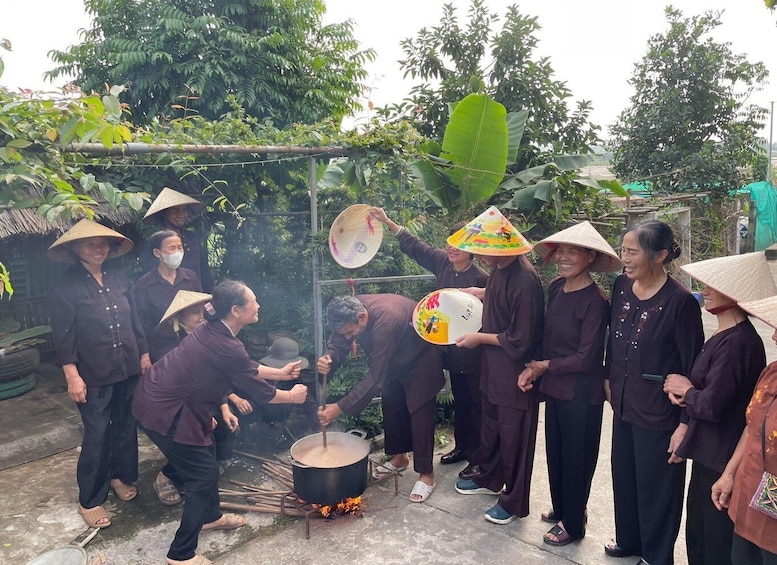 A group of people cooking outdoors, some wearing traditional conical hats. 3
