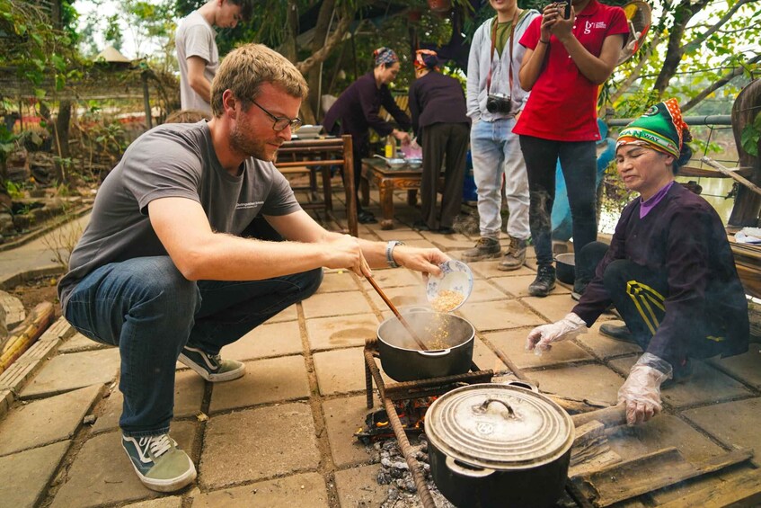 A person cooking outdoors with a pot on a portable stove, surrounded by onlookers. 4