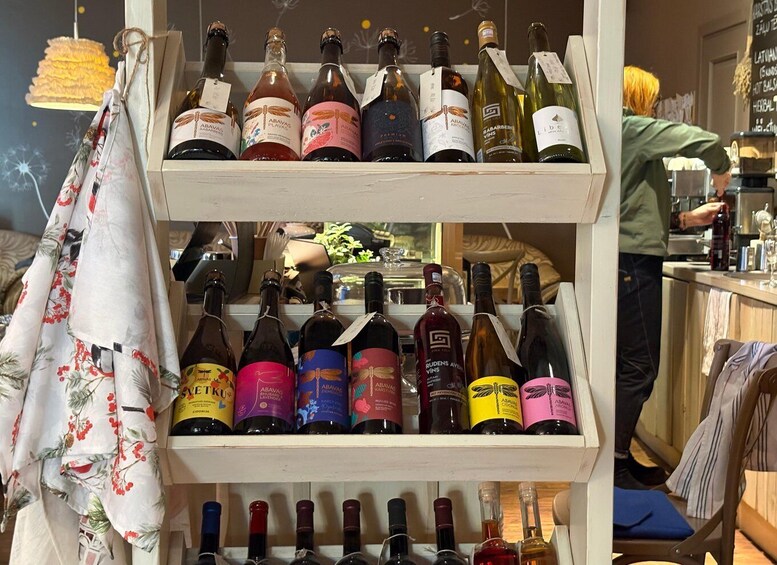 A wine rack with various bottles, a hanging cloth, and a person in the background. 5