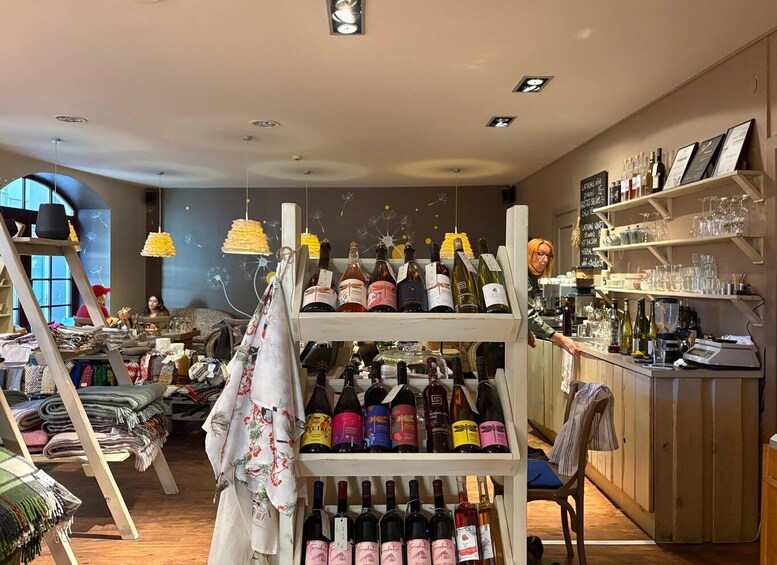 A boutique with shelves of wine bottles and a display of folded blankets. 1