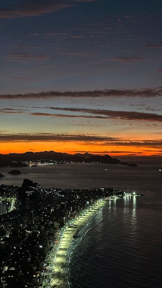 A coastal cityscape at dusk with illuminated streets and a sunset over the water. 4