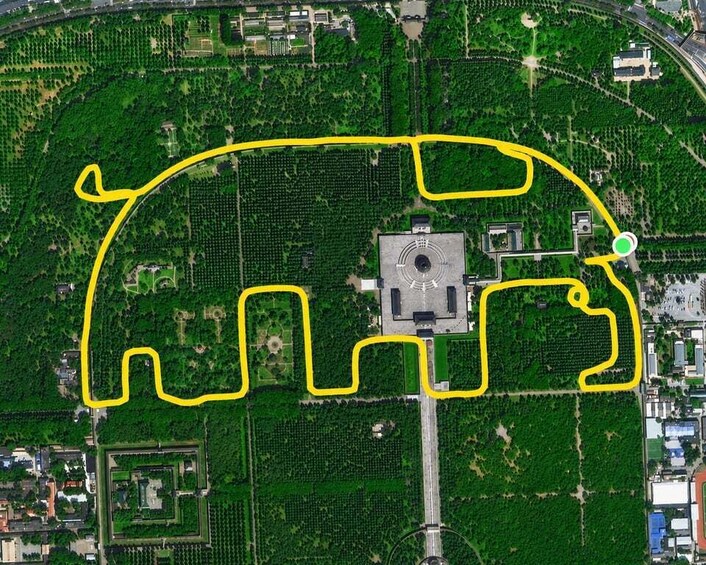 An aerial view of a park with a yellow path shaped like a bull, surrounded by green trees and a central monument. 3