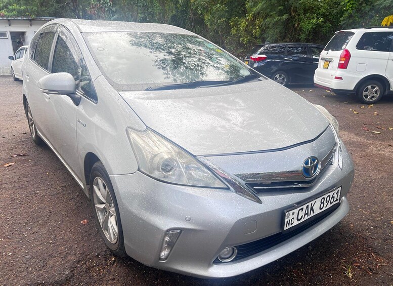 A silver Toyota Prius parked on a dirt surface with trees in the background. 2