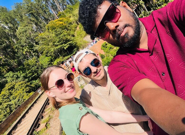 A person taking a selfie with a scenic railway track and lush greenery in the background. 1