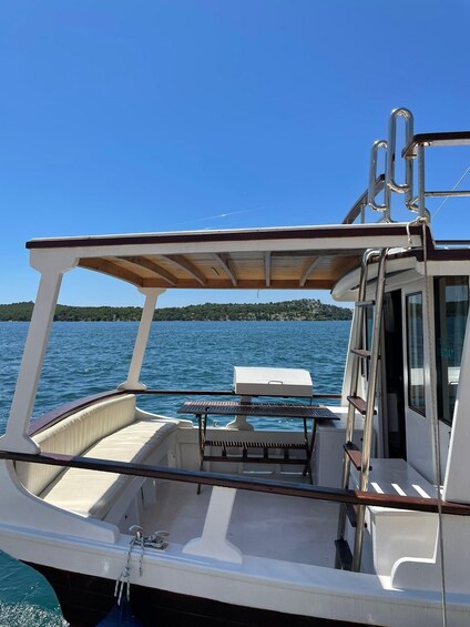 A boat with a covered deck, a grill, and a view of a calm lake with a distant shoreline. 4