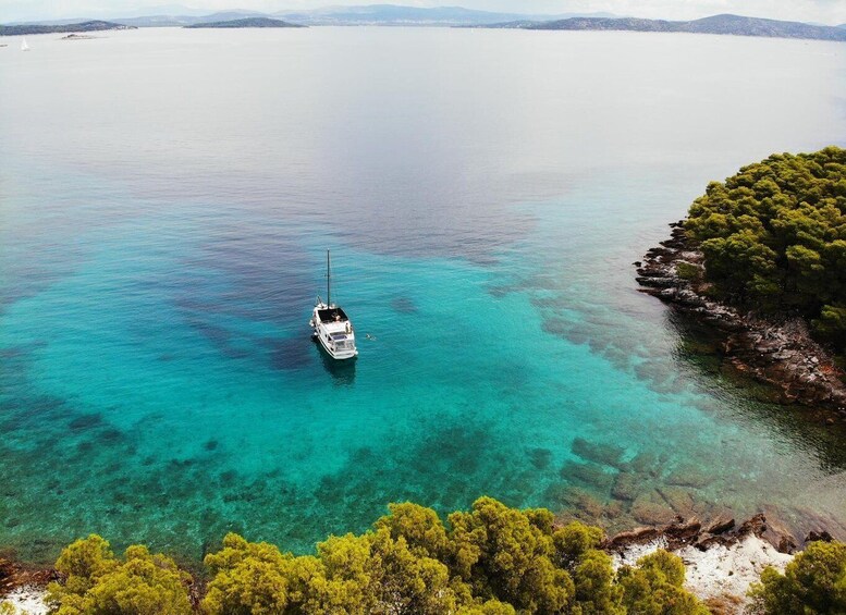 A boat anchored in clear turquoise waters, surrounded by a rocky coastline with dense green vegetation. 3