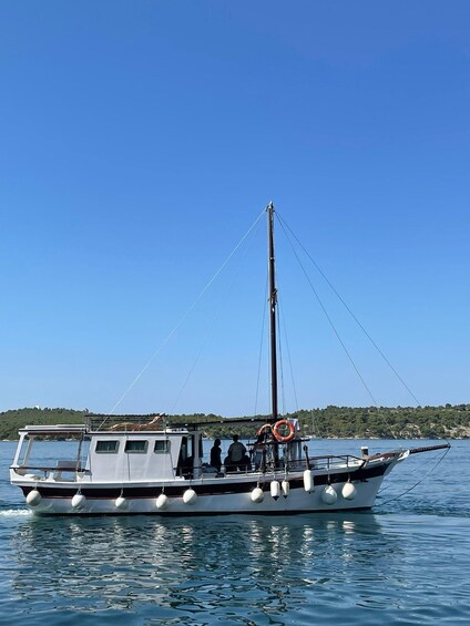 A boat with a mast, life rings, and a person on deck. 1