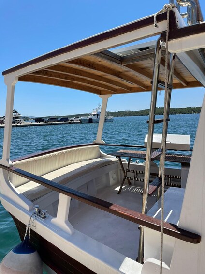 A boat with a wooden deck and a white interior, docked at a marina with other boats and a clear blue sky. 2