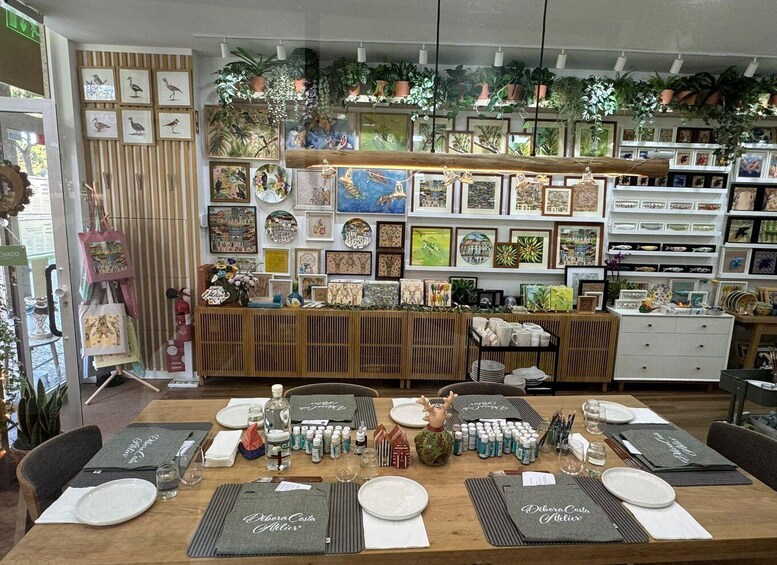 A store with framed artwork, shelves of decorative plates, and a table set for dining. 2