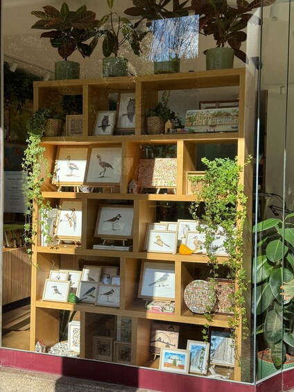 A wooden display case with framed artwork and potted plants. 3