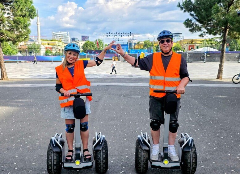 Two people on segways in an urban setting with buildings and trees. 5