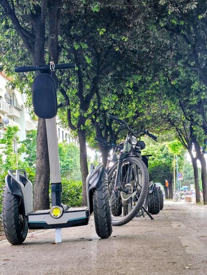 A sidewalk with a parked electric scooter and a bicycle. 2