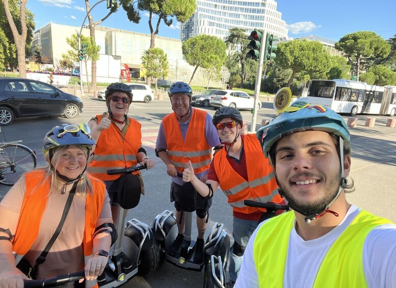A group of people on segways in an urban setting with buildings and traffic lights. 4