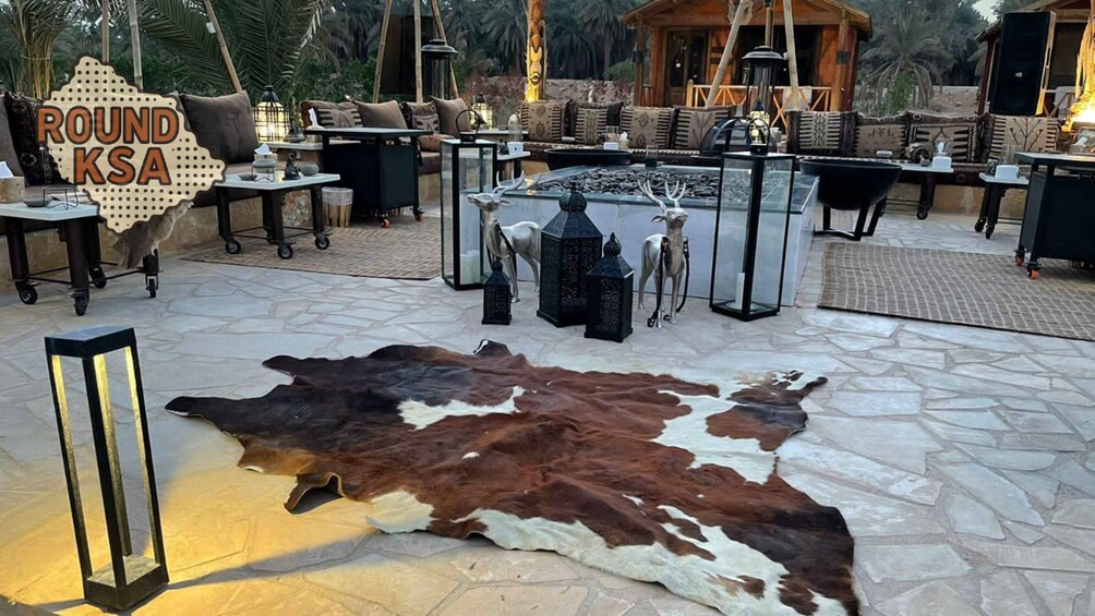 A rustic outdoor seating area with a large cowhide rug, wooden furniture, and decorative lanterns. 2