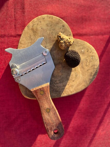 A metal tool with a wooden handle, a round wooden object, and a round, textured object. 3