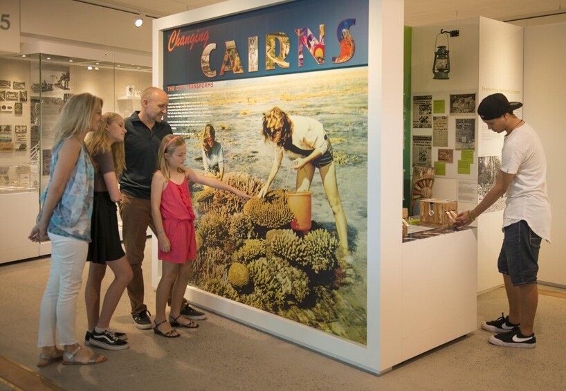A family at an exhibit with a large poster titled 'Changing CARRNS' and a display case with items. 1