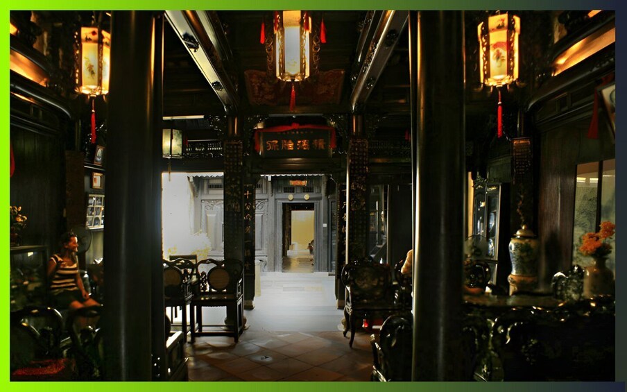 A dimly lit corridor with traditional lanterns, wooden furniture, and Chinese calligraphy on the walls. 5