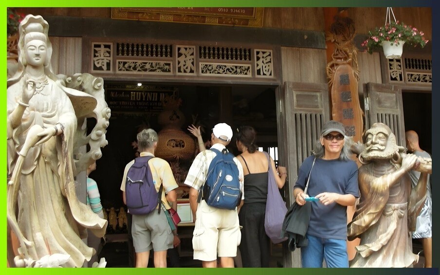 A group of people entering a building with traditional Chinese architectural elements, including intricate carvings and statues. 4