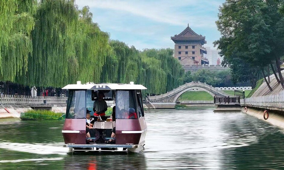 A boat on a river with a bridge and pagoda in the background. 1