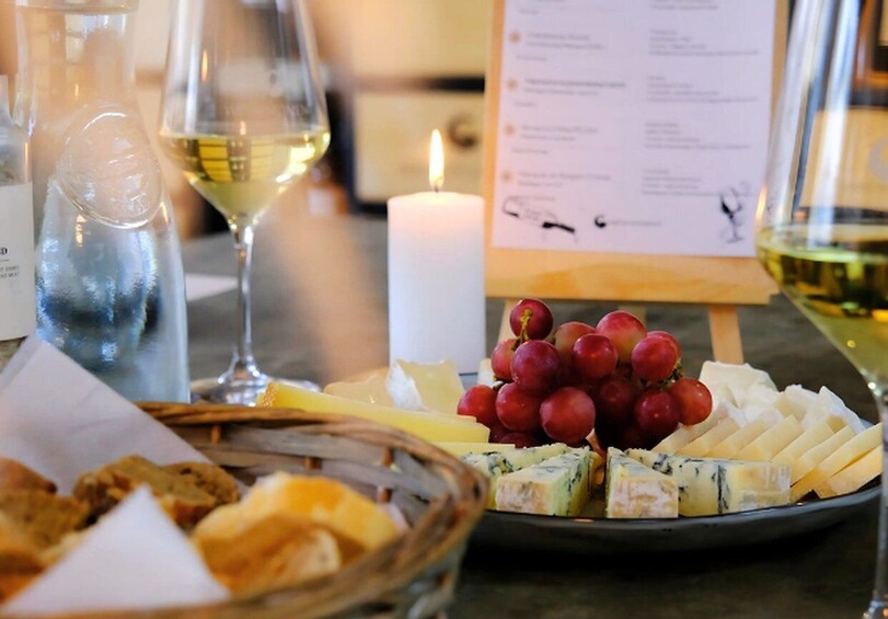 A table with cheese, grapes, bread, and a candle. 1