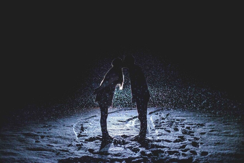 Two people standing on a beach at night, silhouetted against the sky. 4