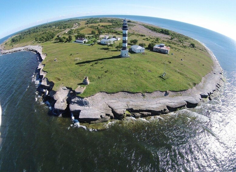 An aerial view of a coastal area with a lighthouse, grassy terrain, and rocky shoreline. 4