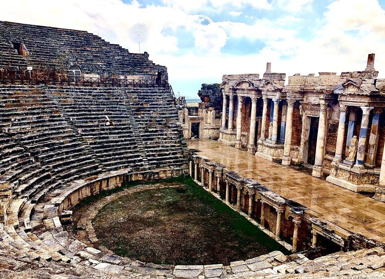 An ancient amphitheater with tiered seating and a central stage. 2