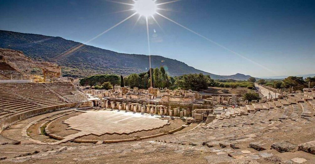 An ancient amphitheater with stone seating and ruins. 5
