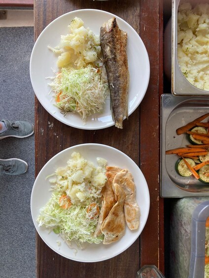 Two plates of food with fish, potatoes, and vegetables. 5