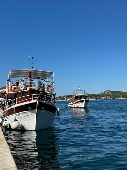 Two boats docked at a pier with calm water and a clear sky. 3