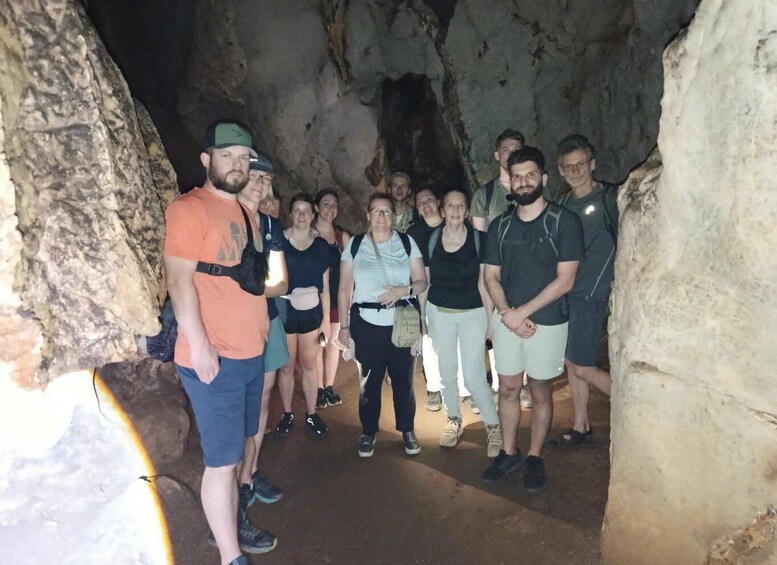 A group of people inside a cave with rocky walls and a narrow passageway. 5