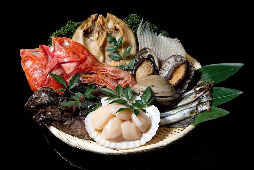 A variety of seafood including shrimp, scallops, clams, and fish, arranged on a woven basket with green leaves. 2