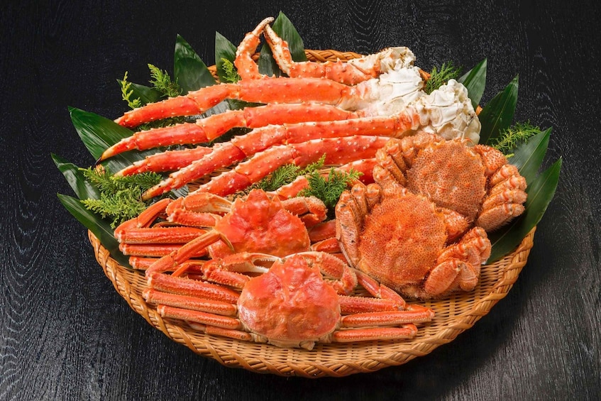 A basket of cooked crab legs and claws on a dark surface. 1