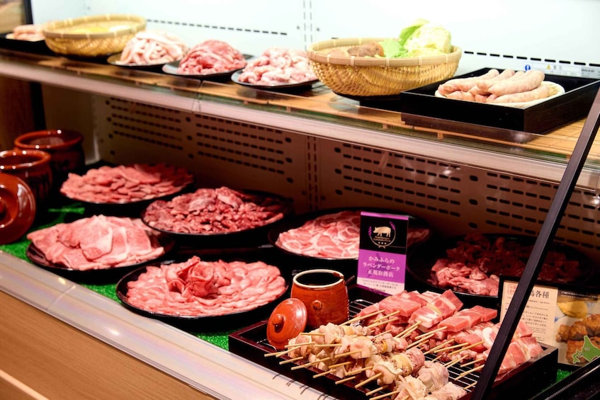 A variety of raw meats and skewers on display in a refrigerated section of a market. 4