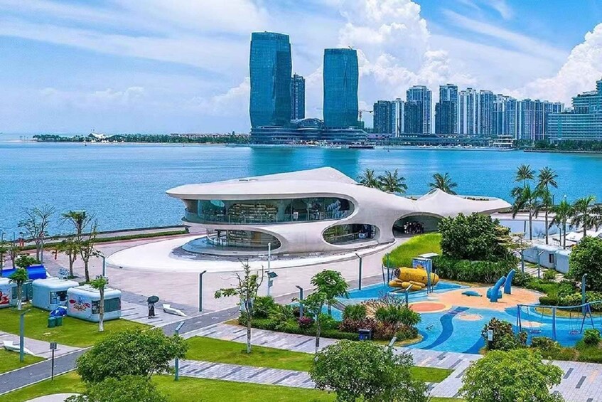 A waterfront park with modern architecture, a pool, and a city skyline in the background. 3