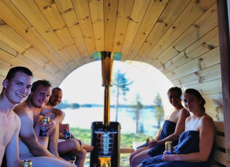 A group of people sitting under a wooden structure with a sauna in the background. 4