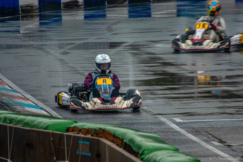 Go-karts on a wet track with barriers and a green safety net. 3