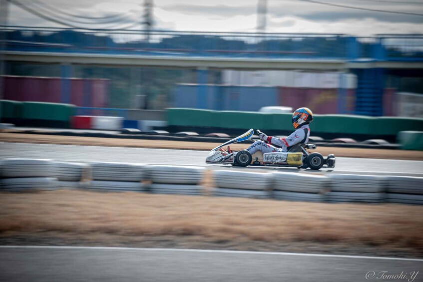 A go-kart racing on a track with barriers and a cloudy sky. 2