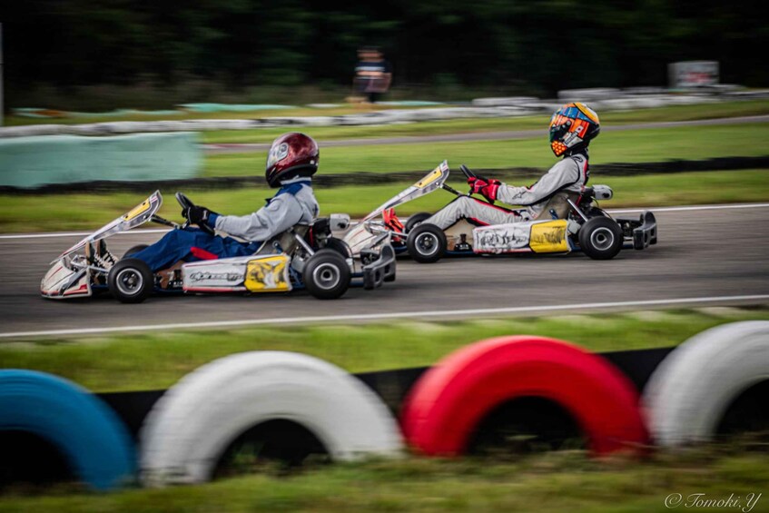 Two go-karts racing on a track with tires and barriers. 1
