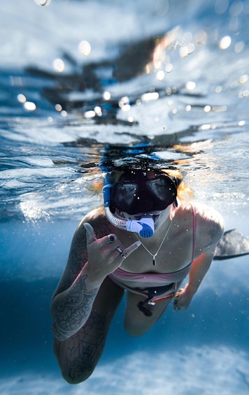 A person underwater, wearing a snorkel and mask, with tattoos on their arm. 1
