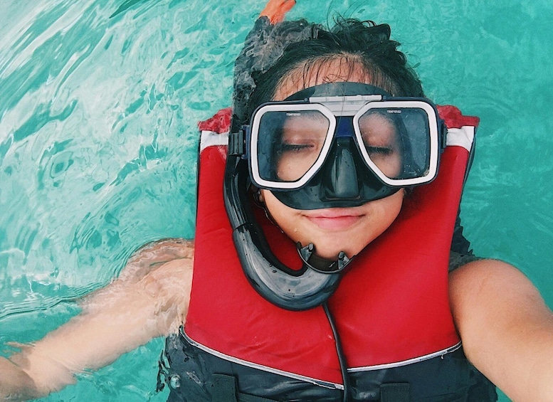 A person snorkeling in a pool with a red life jacket and black fins. 5