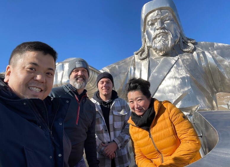 A group of people standing in front of a large metallic sculpture. 4