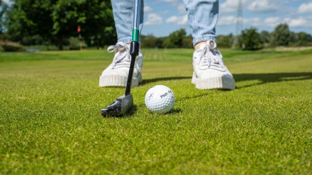 A golf ball on a green with a putter nearby. 5