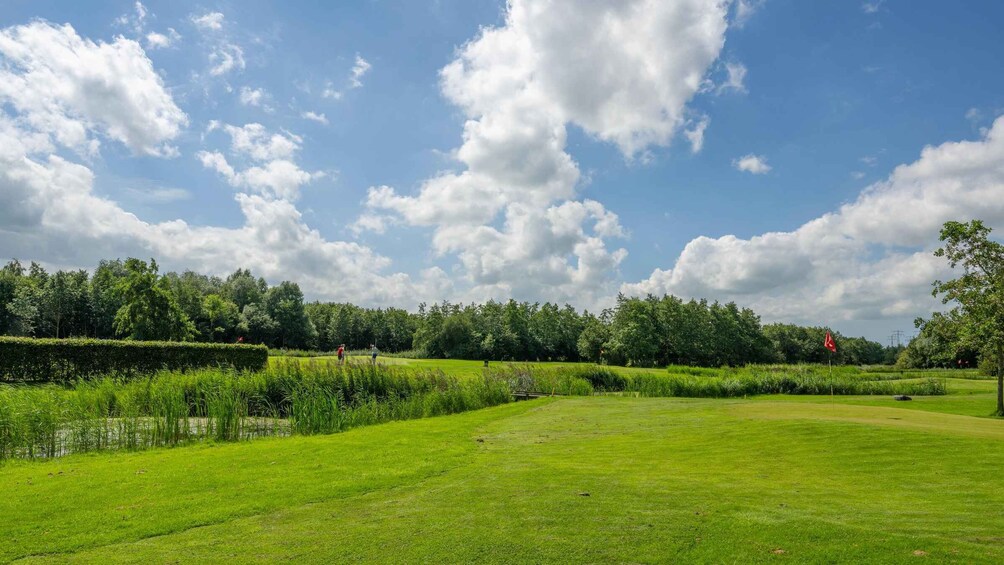 A golf course with lush green grass, trees, and a partly cloudy sky. 3