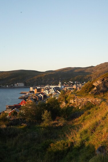 A coastal town with a prominent church, rolling hills, and a body of water. 2