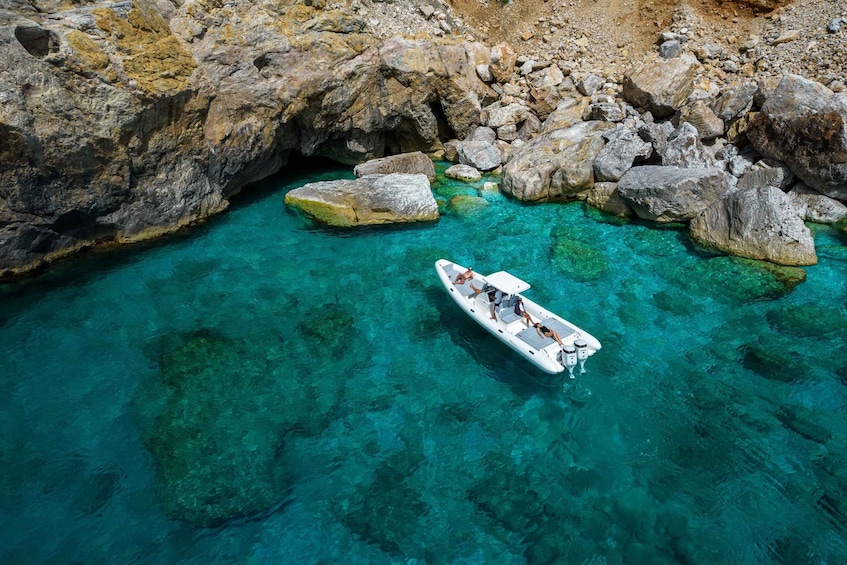 A boat on clear turquoise water surrounded by rocky terrain. 5