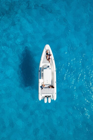 A white boat with two people on board, floating on clear blue water. 3