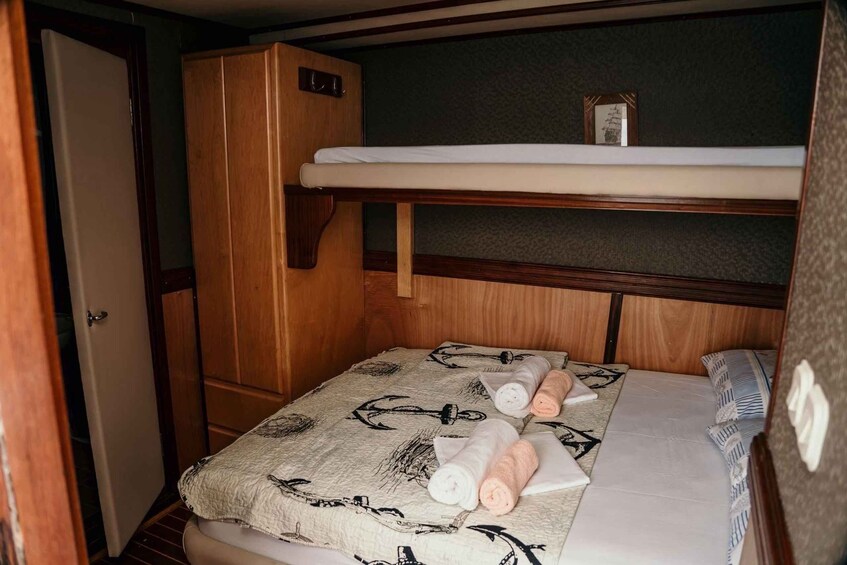 A compact cabin with a bunk bed, a wooden wardrobe, and a small shelf with a framed picture. 5