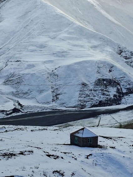 Un paysage enneigé avec une petite maison en pierre et une route. 5