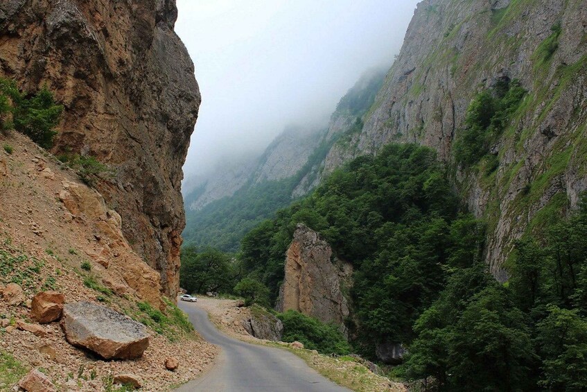 Une route de montagne sinueuse, bordée de falaises rocheuses et d’une forêt dense. 2